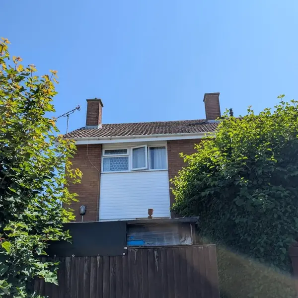 Rear of a brick terraced house showing the tiled roof and two chimney stacks
